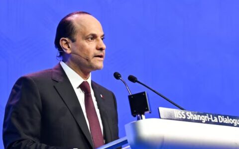 A suited speaker addressing an audience from a lectern