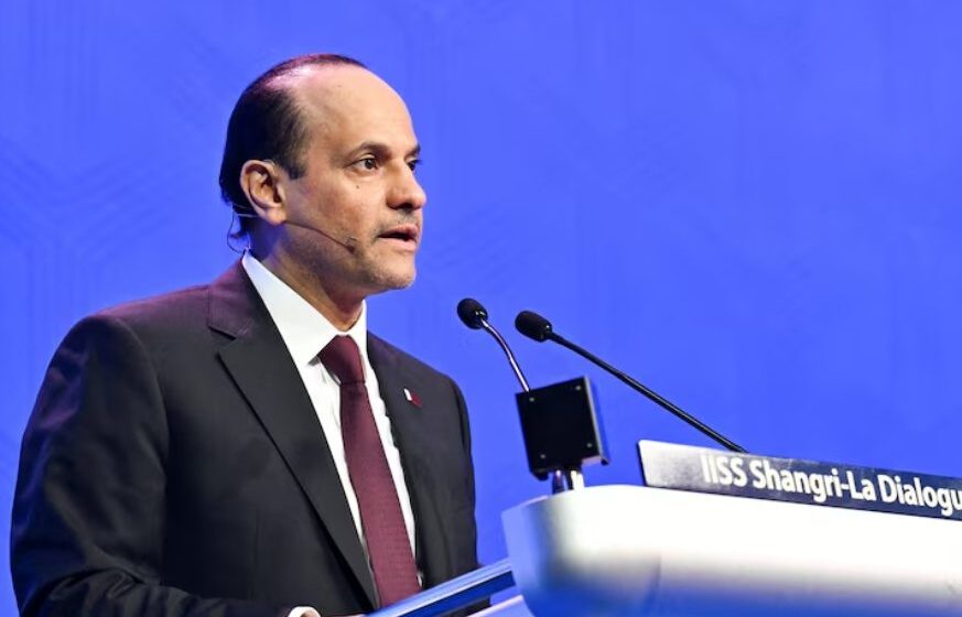 A suited speaker addressing an audience from a lectern